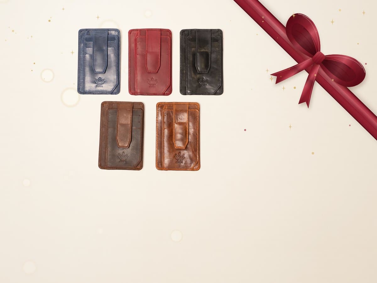 Three ROYAL leather card holders in dark brown, burgundy and cognac on a warm cream surface